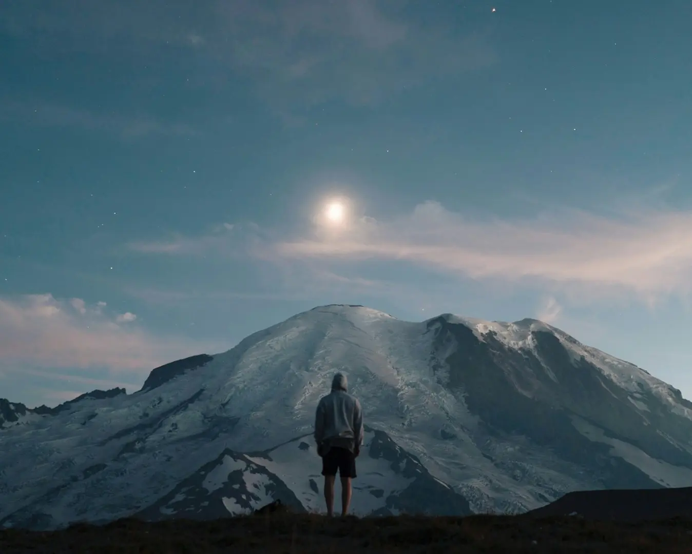 Person vor schneebedecktem Berg unter Mond